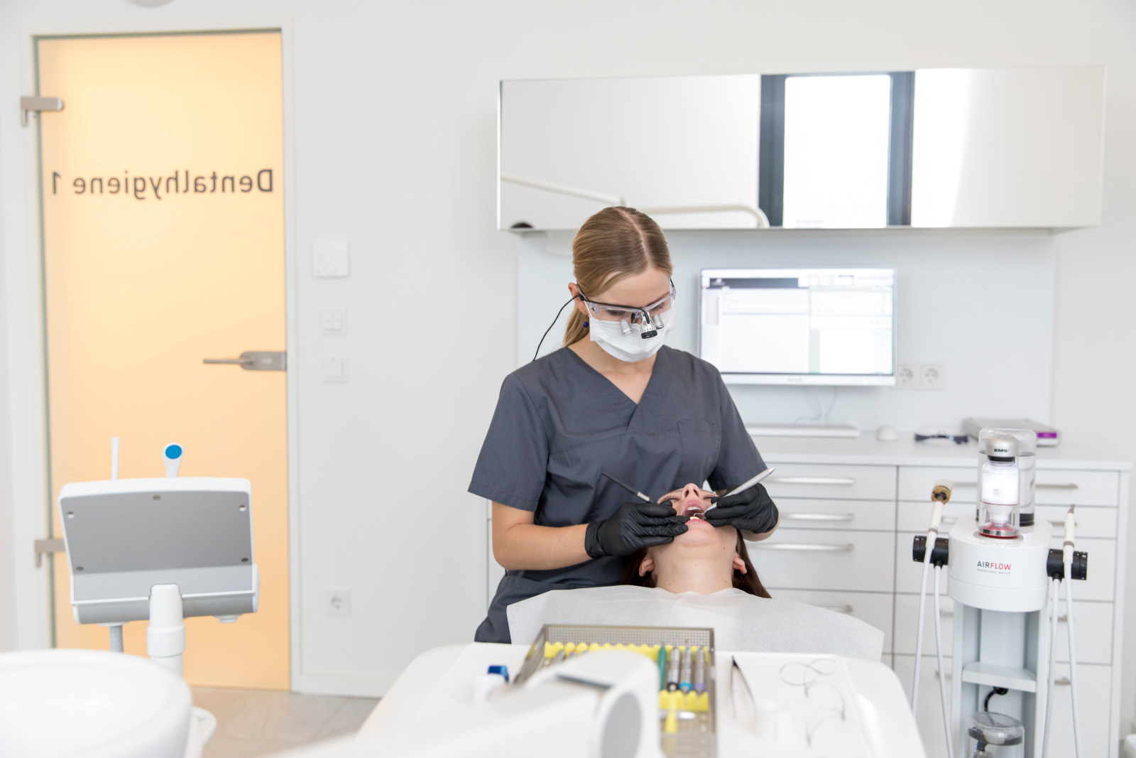 Prophylaxe-Praxis: Die Dentalhygienikerin (DH) entfernt Plaque und Zahnstein, eine wichtige vorbeugende Maßnahme für den langfristigen Zahnerhalt.